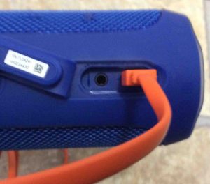 Picture of the orange micro USB charge cable inserted into the speaker power port.