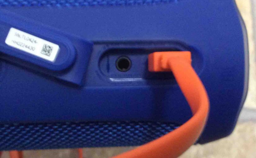 Picture of the JBL Flip 4 waterproof speaker with its orange micro USB charge cable inserted.