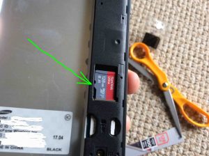 Picture of a new microSD memory card positioned in slot in phone but not yet snapped into place.