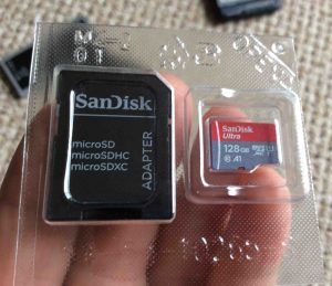 Picture of the Sandisk Ultra 128 GB memory card and adapter, showing inner plastic package, front view.