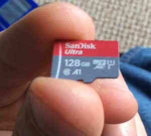 Picture of the SanDisk 128 GB Ultra MicroSDXC memory card, front view, held in hand.