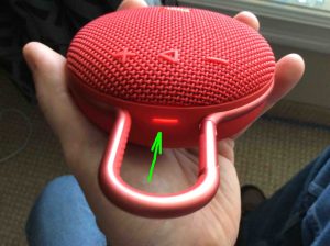 Picture of the JBL Clip 3 Bluetooth wireless speaker, top view, status lamp glowing red.