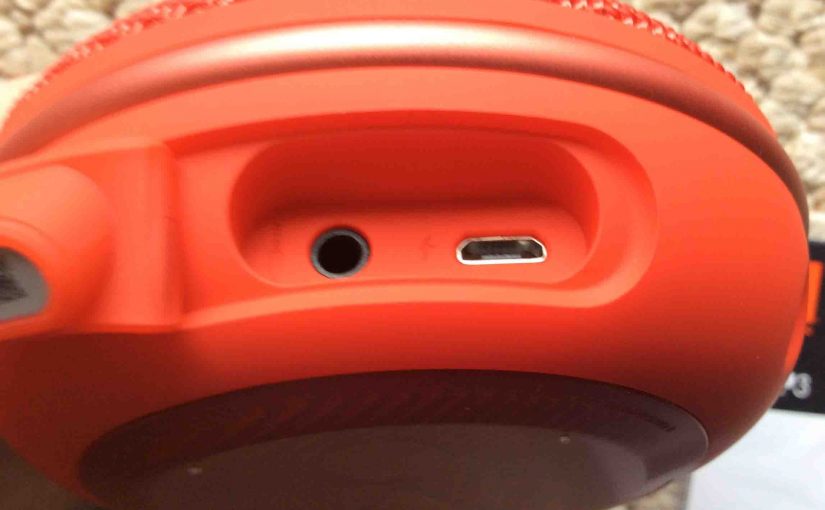 Picture of the JBL Clip 3 waterproof speaker, bottom view, port door open. showing the USB charging port and audio input port.