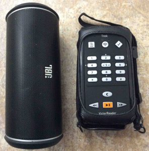Picture of the JBL Flip 2 Bluetooth speaker alongside the Humanware Victor Reader Trek talking book player and GPS navigator.