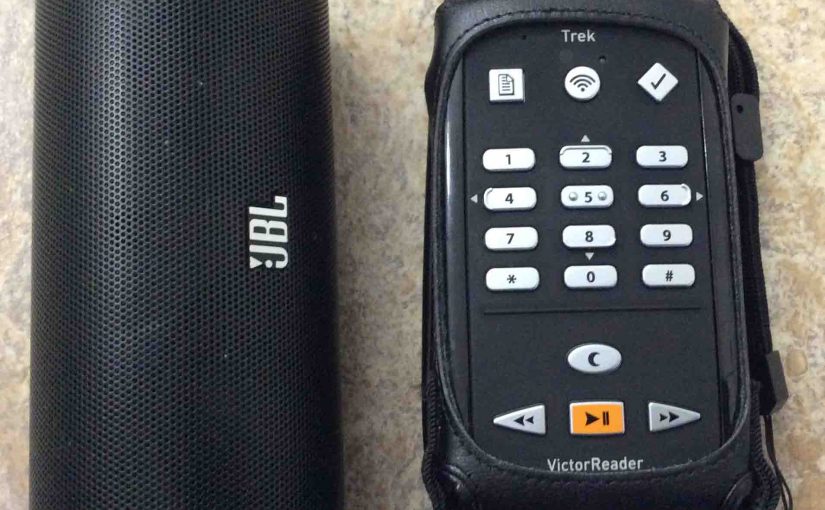 Picture of the JBL Flip 2 Bluetooth speaker alongside the Humanware Victor Reader Trek talking book player and GPS navigator.