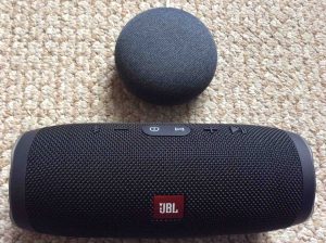 Picture of a Google Home Mini Smart Speaker with a JBL Charge 3 Bluetooth speaker.