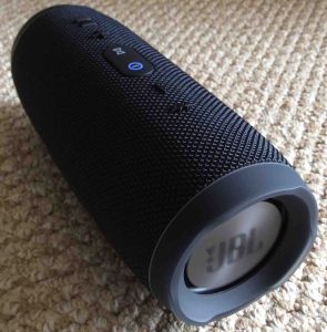 Picture of the JBL Charge 3 portable rechargeable speaker. Showing its left end. This Bluetooth speaker is powered on and paired.