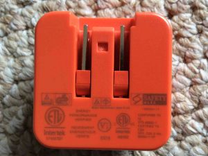 Picture of the JBL AC power adapter, mains side view, Showing the safety labels.