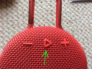 Picture of the JBL Clip 3 splashproof speaker, front view. Showing its Play-Pause button highlighted.
