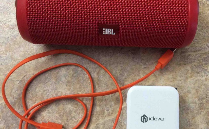 Picture of the JBL Flip 3 battery operated speaker, with its USB charging cable along with an iClever 3 port USB wall charger.