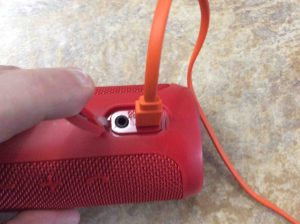 Picture of the JBL Flip 3 portable Bluetooth speaker, with the included USB charge cord connected.