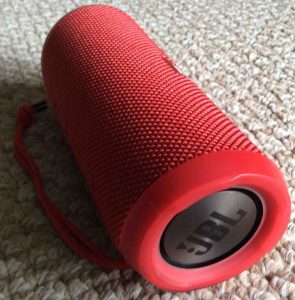 Picture of the JBL Flip 3 wireless speaker, red version, showing its back and left end passive radiator.