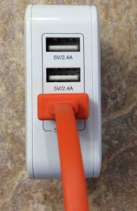 Picture of the iClever 3-Port USB wall charger, model IC-TC03. Showing its USB port side with a USB cable plugged into one of its output ports.
