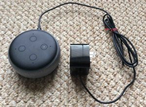 Picture of an Amazon Echo Dot smart speaker along with its AC wall adapter. Alexa Set Up Instructions.