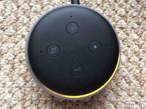 Picture of an Amazon Alexa Echo Dot speaker, shown in Setup mode, light ring orange and spinning.