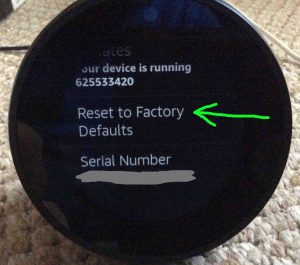 Picture of the Amazon Echo Spot smart speaker, showing the Reset To Factory Defaults option highlighted on its Device Options screen.