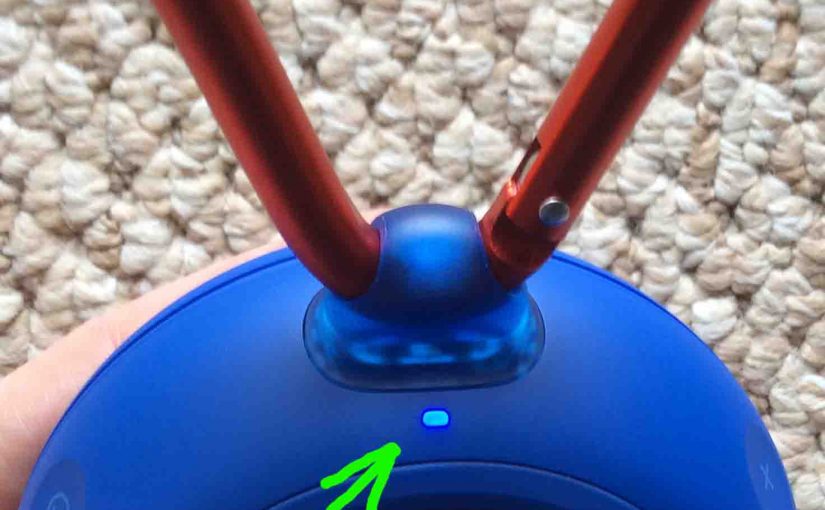 Picture of the JBL Clip 2 speaker, top rear view, powered on. showing the status lamp glowing blue highlighted.
