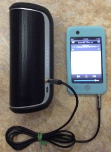 Picture of the JBL Flip 2 Bluetooth speaker, playing from an iPod Touch via its AUX input port.