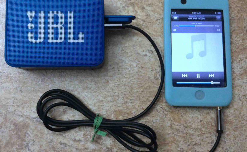 Picture of the JBL Go 2 Bluetooth speaker, connected via its AUX input to an iPod Touch portable media player.