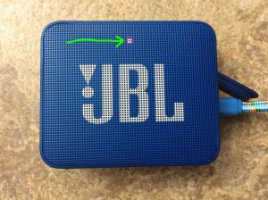 Picture of the JBL Go 2 Bluetooth speaker front view, highlighting the red status light, meaning that the speaker is charging.