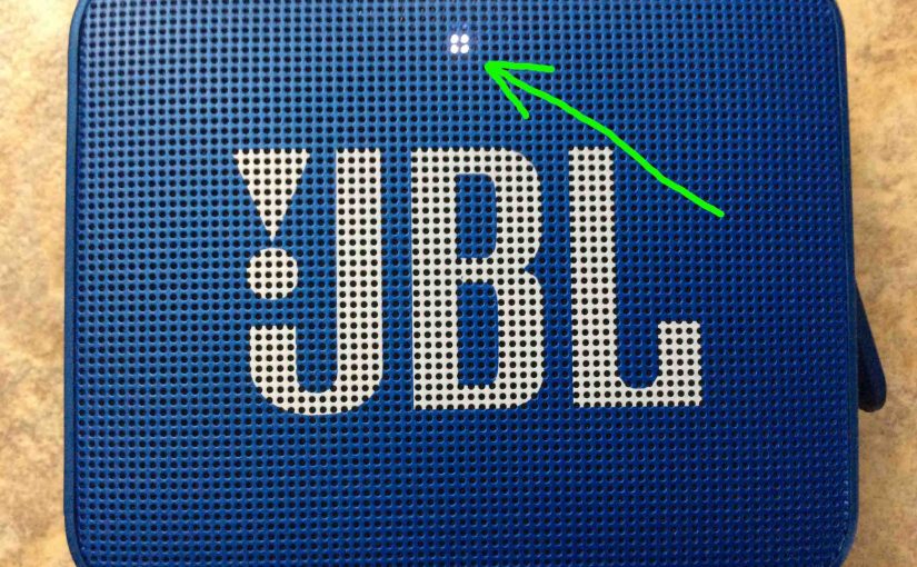Picture of the JBL Go 2 portable speaker, front view, with the Power / Status lamp glowing white, highlighted.