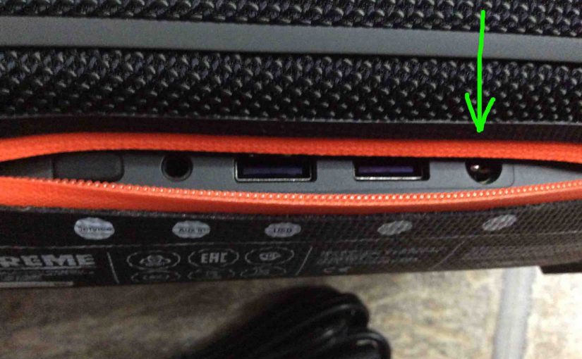 Picture of the JBL Xtreme Bluetooth speaker, rear view, showing its ports zipper open, with the power input charging port highlighted.
