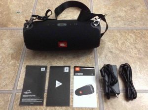 Picture of the unboxed speaker with accessories, showing the charger, strap, and manuals. JBL Extreme Specifications.
