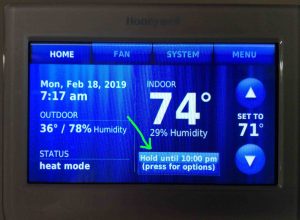Picture of the thermostat displaying its -Home- screen, with the -Hold- button showing -Temporary Hold- mode highlighted.