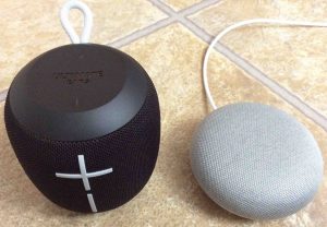 Picture of the The Google Home Mini smart speaker (right) with a typical Bluetooth speaker (left). 