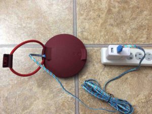Picture of the UE Roll speaker, back view, connected to USB power and charging.
