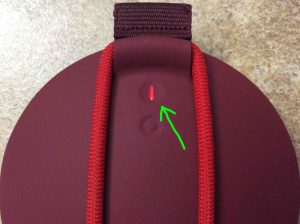 Picture of the UE Roll Bluetooth speaker, back view, showing the red glowing Power button, that means low battery, highlighted.