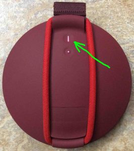 Picture of the Ultimate Ears Roll speaker back view.. Speaker is turned ON. Showing the glowing -Power- button highlighted.