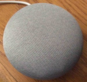 Picture of the Google Home Mini speaker, gray model, top view, with all lights OFF.
