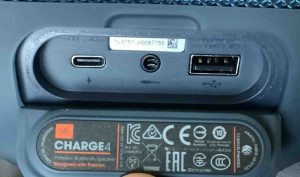 Picture of the JBL Charge 4 wireless speaker, back view, showing the port access panel open.