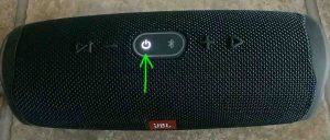 Picture of the JBL Charge 4 wireless speaker, top view, showing the glowing Power button highlighted.