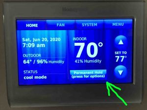 Picture of a typical thermostat, displaying its -Home- screen, with the -Permanent Hold- button highlighted.