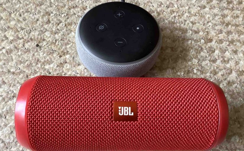 JBL Flip 3 beside an Amazon Alexa Echo Dot 3 speaker.