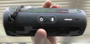 Picture of the JBL Flip 5 powered ON, held in hand. Note that the entire battery gauge bar on the right is lit, to indicate a fully charged battery.