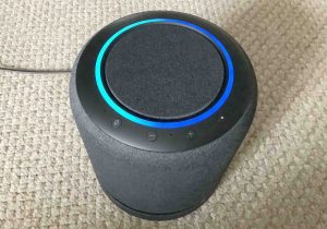 Front top view picture of the Echo Studio Alexa, showing the blue green light ring as the speaker boots.