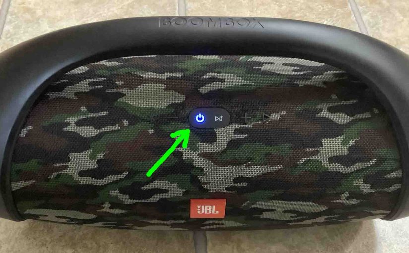 The -Power- button glowing blue on the JBL Boombox Bluetooth speaker.