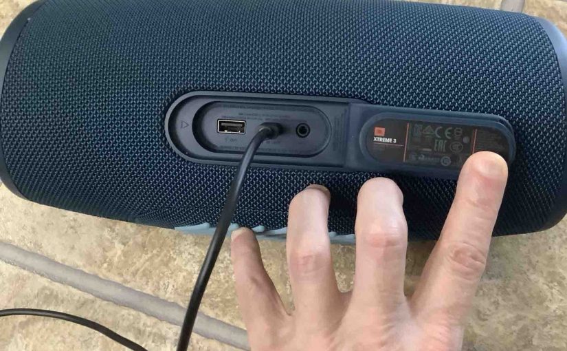 The charger cable inserted into the back of the JBL Xtreme 3 Bluetooth speaker.