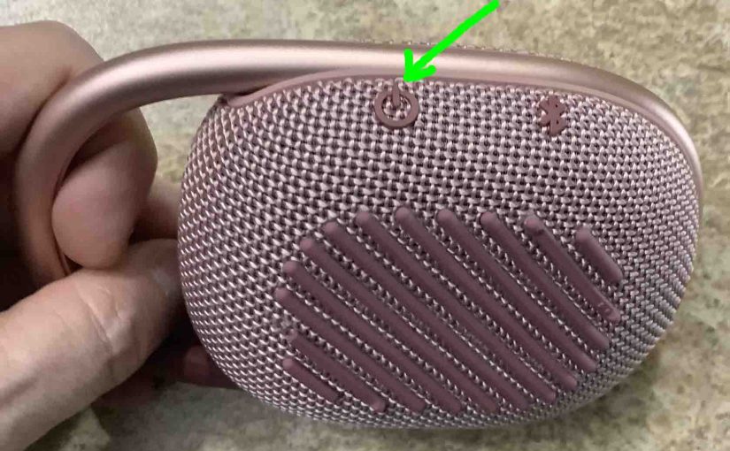 Picture of the -Power- button on the left side of the JBL Clip 4 speaker.
