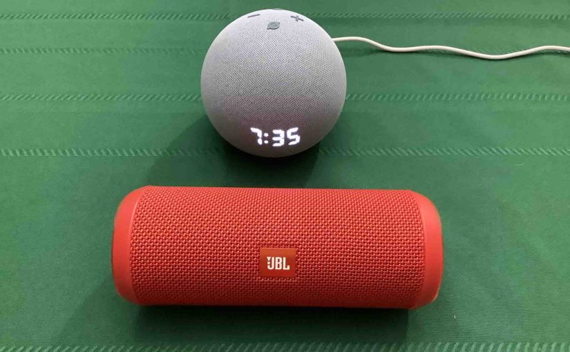 Picture of the JBL Flip 3 BT speaker in Front of an Echo Dot 4 clock speaker,