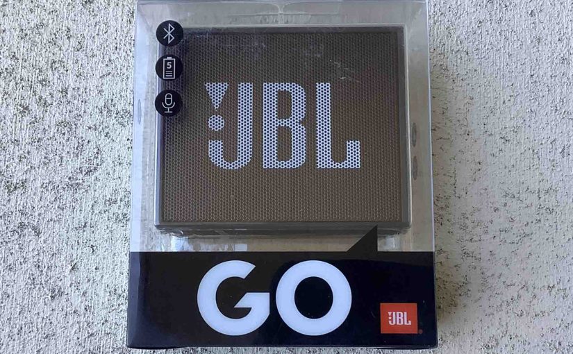Picture of the JBL Go speaker in original transparent carton, front view.