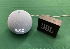 Picture of an Echo Dot 4 clock speaker beside a JBL Go 1 BT speaker
