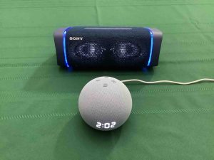 Picture of an Echo Dot 4th Gen clock speaker in front of a Sony XB33 light show and Bluetooth speaker.