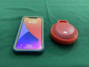 Picture of an iPhone beside the JBL Clip 1 Bluetooth speaker.
