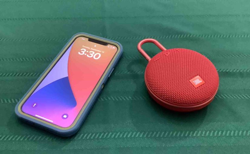 Picture of an iPhone beside the JBL Clip 3 speaker.