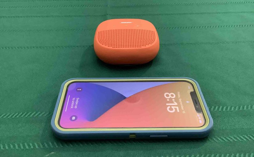 Picture of an iPhone sitting in front of the Bose SoundLink Micro Bluetooth speaker.