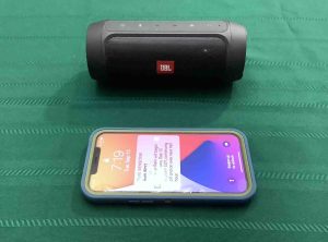 Picture of an iPhone in front of the JBL Charge 2+ wireless speaker.